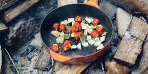 frying pan of food over a campfire
