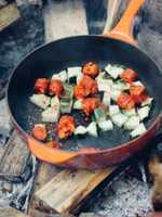 frying pan of food over a campfire