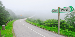 a road with a road sign pointing to past and present